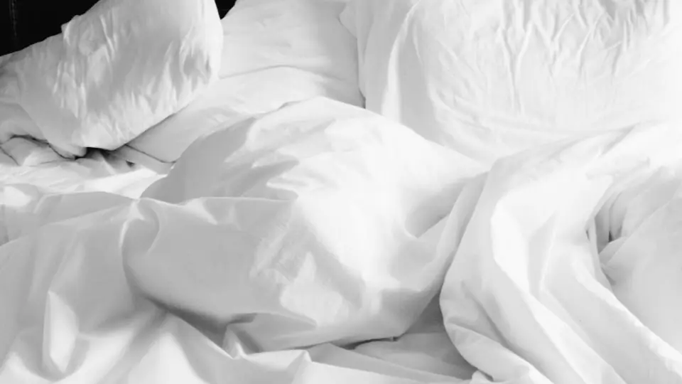 Krøllede hvide lagner og puder på en seng, et billede på sexdating uden forpligtelser