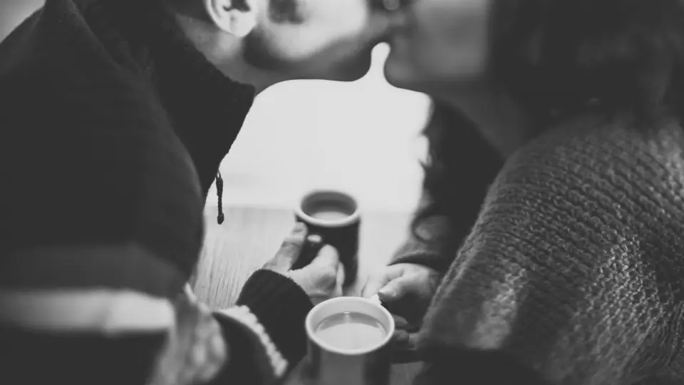 Sexdating Aarhus: et par kysser med kaffekopper i hænderne, i sort-hvid