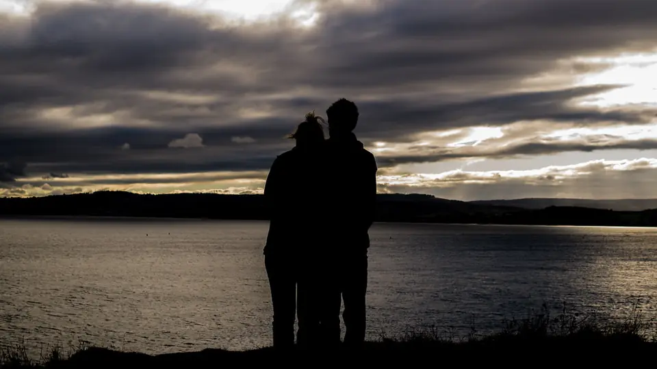Sexdating Næstved: silhuetten af et par ved vandet under mørke skyer